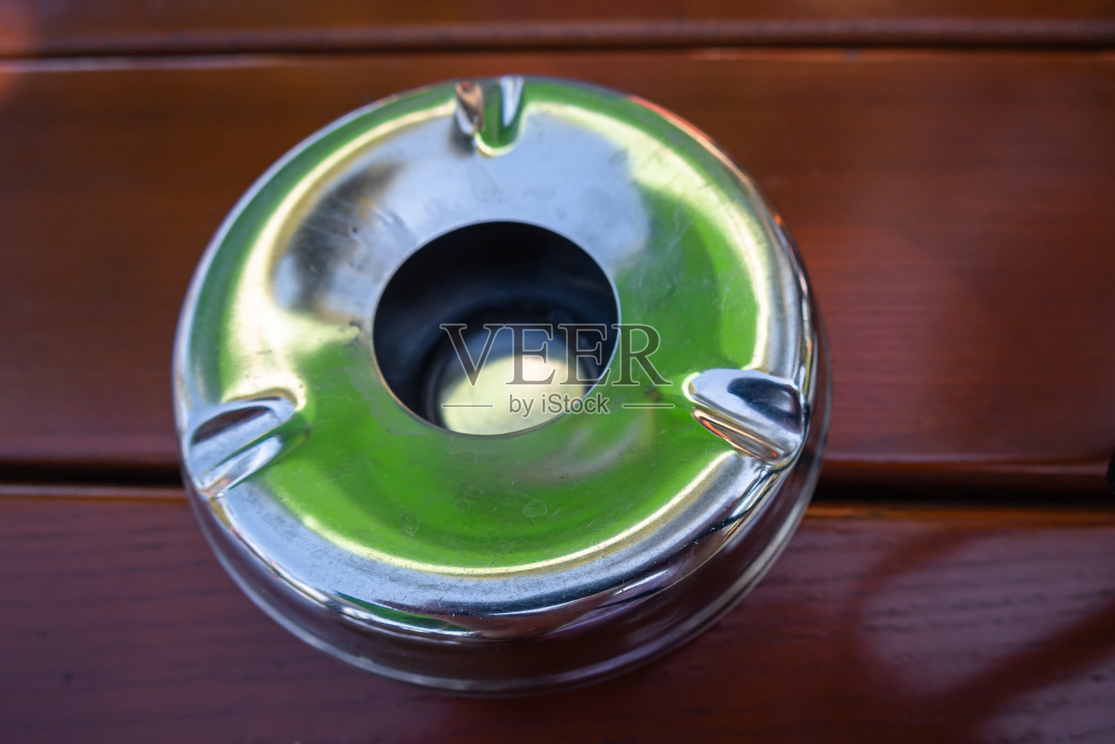 烟灰缸放在树下花园的桌子上照片摄影图片