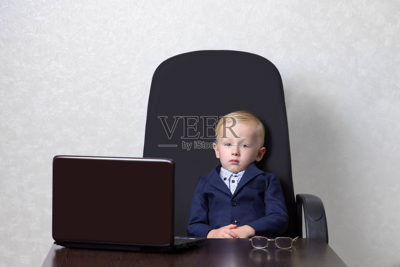 一个男孩坐在办公室的椅子上照片摄影图片