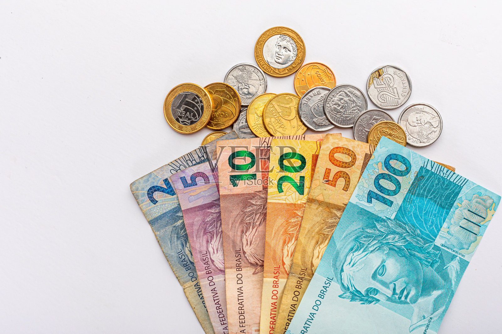 白色背景的巴西货币，有一百五十雷亚尔、二十雷亚尔、十雷亚尔、五雷亚尔和二雷亚尔，有不同价值的硬币。金融危机和雷亚尔贬值。照片摄影图片