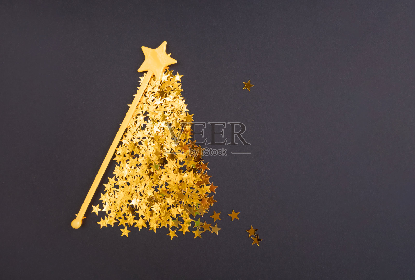 抽象的圣诞树由金色的星星组成，在黑色的背景上留出文字空间。明信片模板,海报。照片摄影图片