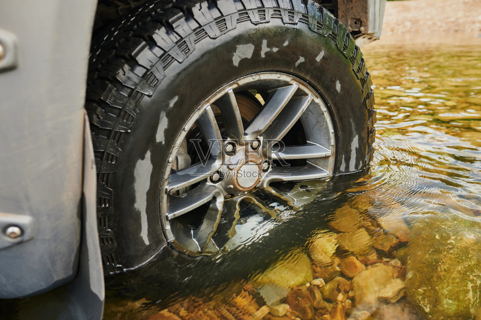 四轮驱动的农用车辆在国家公园的森林里穿过一条被洪水淹没的浅滩。照片摄影图片