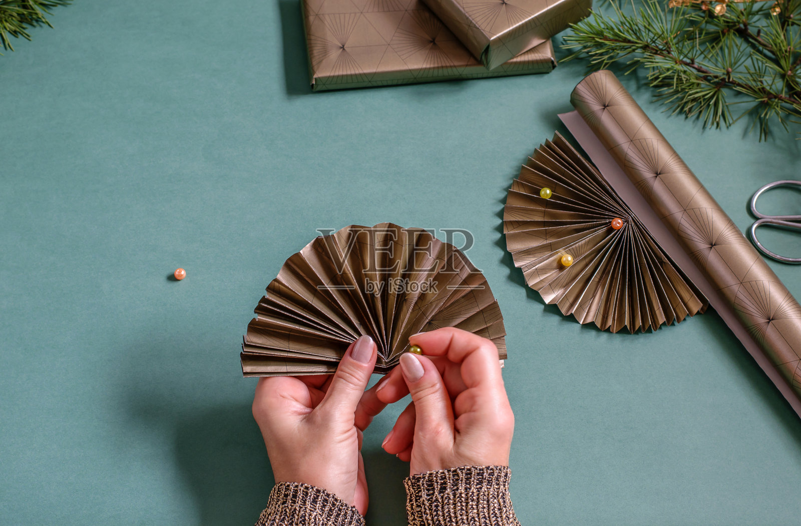 女性双手捧着中国纸扇和珠子越过桌子。家居装饰，精心包装的礼品，diy概念。照片摄影图片