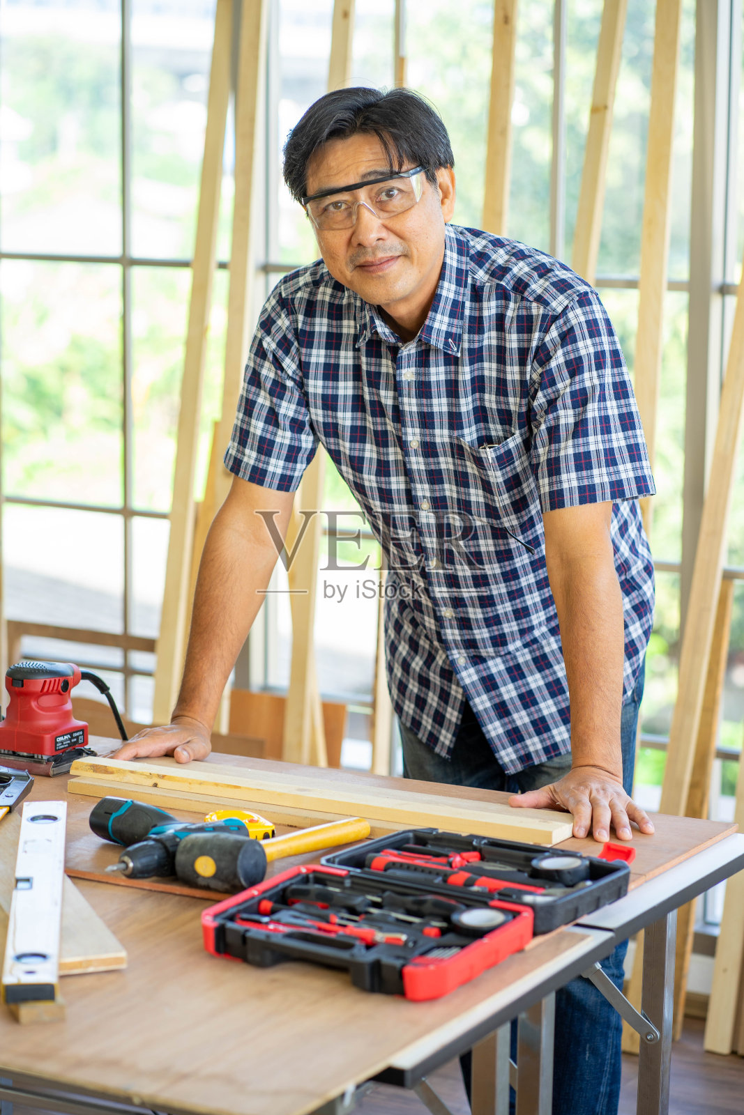 专业亚洲工程师戴安全帽在车间木板施工现场安全工作。在家工作新常态的概念。照片摄影图片