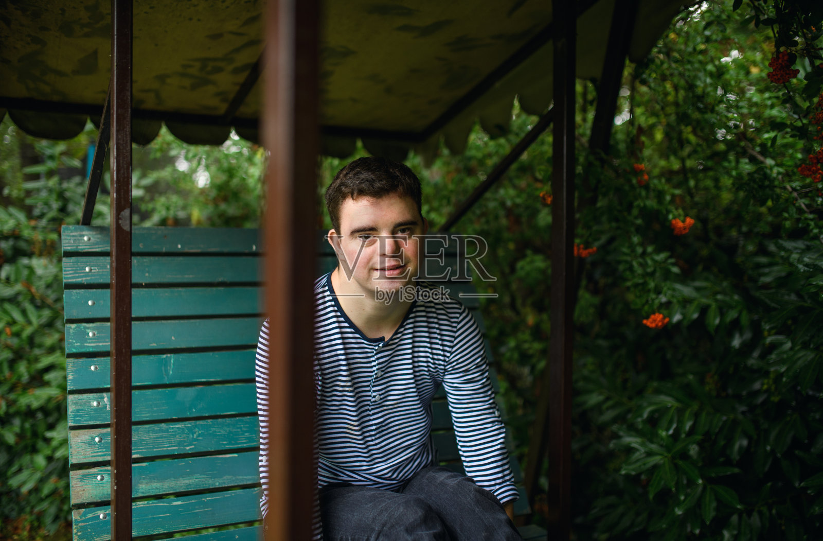 坐在花园里看镜头的唐氏综合征成年男子肖像照片摄影图片