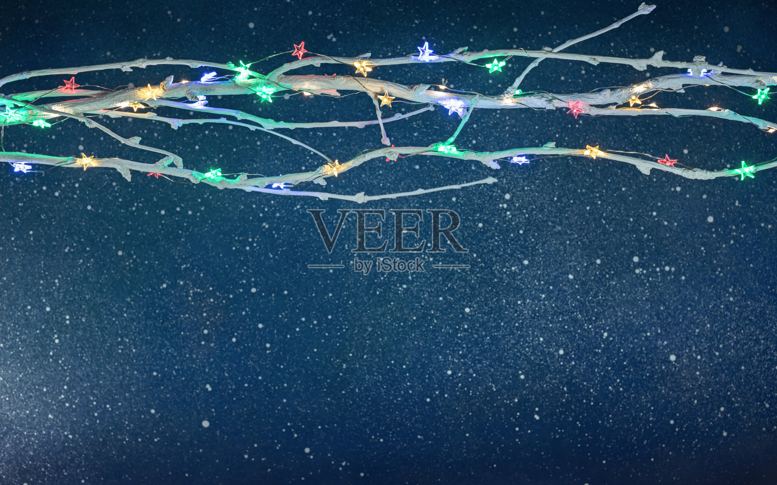 圣诞树的树枝与发光的彩色圣诞灯在深蓝色的背景照片摄影图片