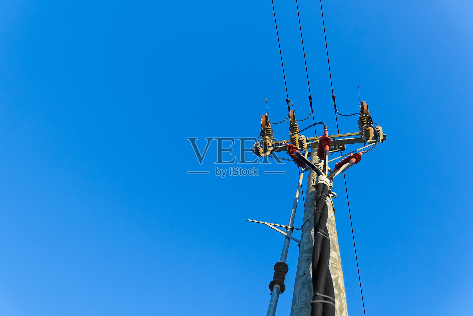 电力线和连接在木柱上。蓝色天空下的木制电线杆。电线电线与蓝天同在。照片摄影图片