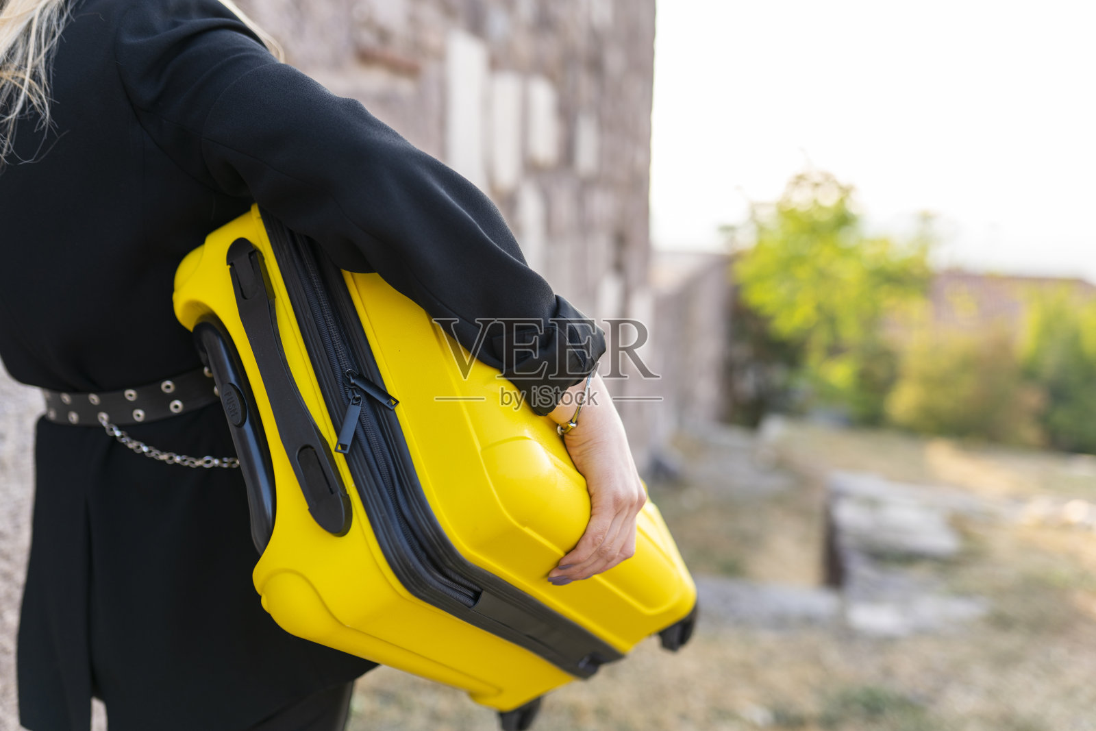 一个优雅的女人带着一个黄色的手提箱在街上旅行照片摄影图片