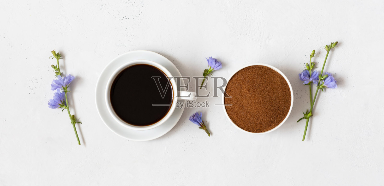 菊苣饮料，菊苣粉在碗和蓝色的花在白色的背景。草本咖啡替代品。俯视图，平放。照片摄影图片