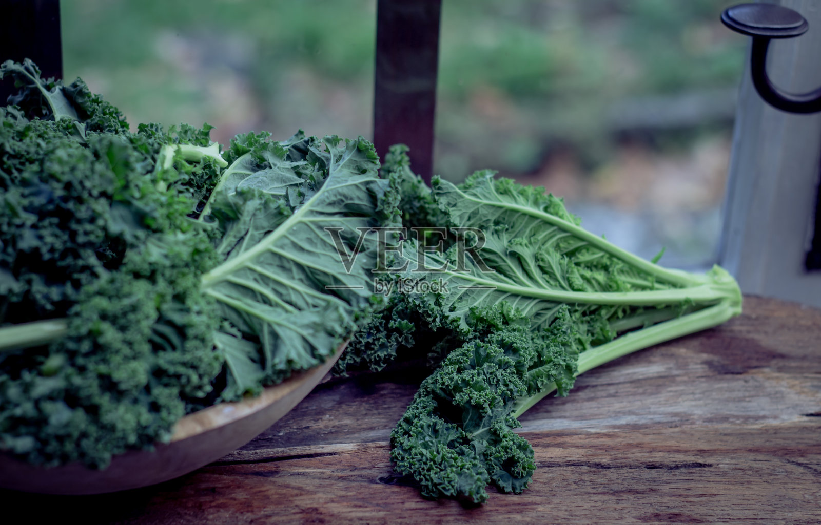 质朴的木碗上放着绿甘蓝，窗户上放着桌子，灯光背景下，超级食物静物，红酒照片摄影图片