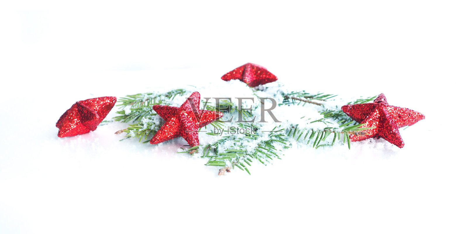 圣诞横幅上的红星在白雪皑皑的杉树枝上闪闪发光。照片摄影图片