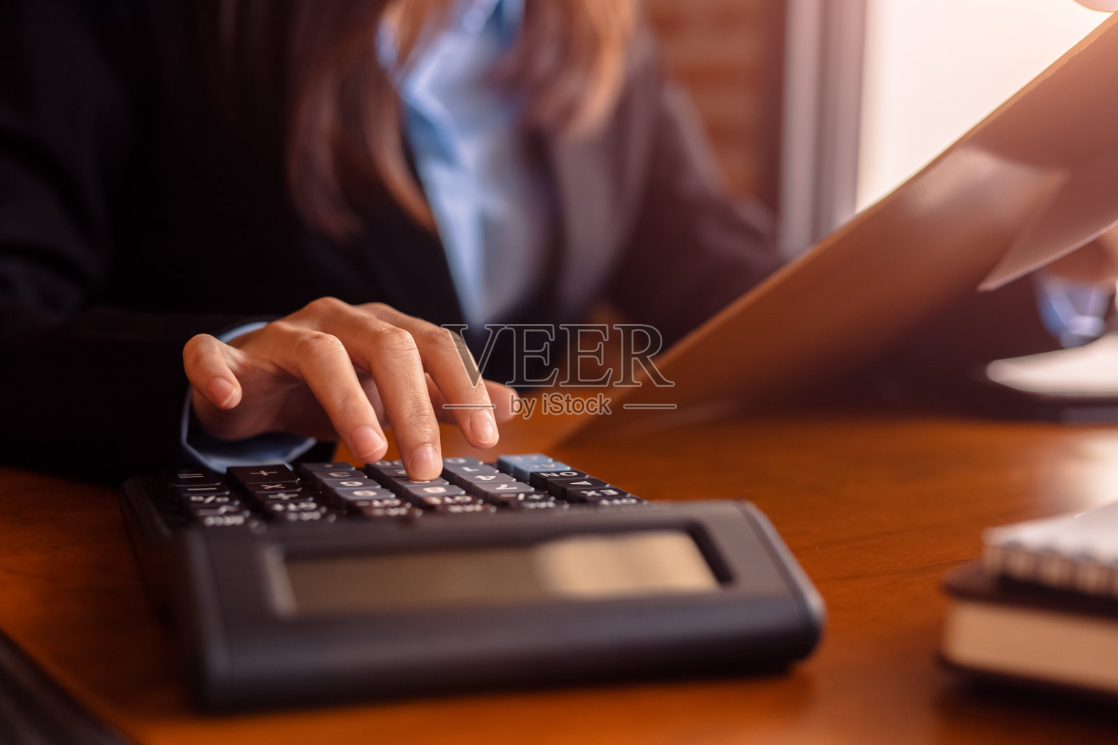 在办公室的桌子上使用计算器和商业文件的商务女性。财务会计的概念。照片摄影图片