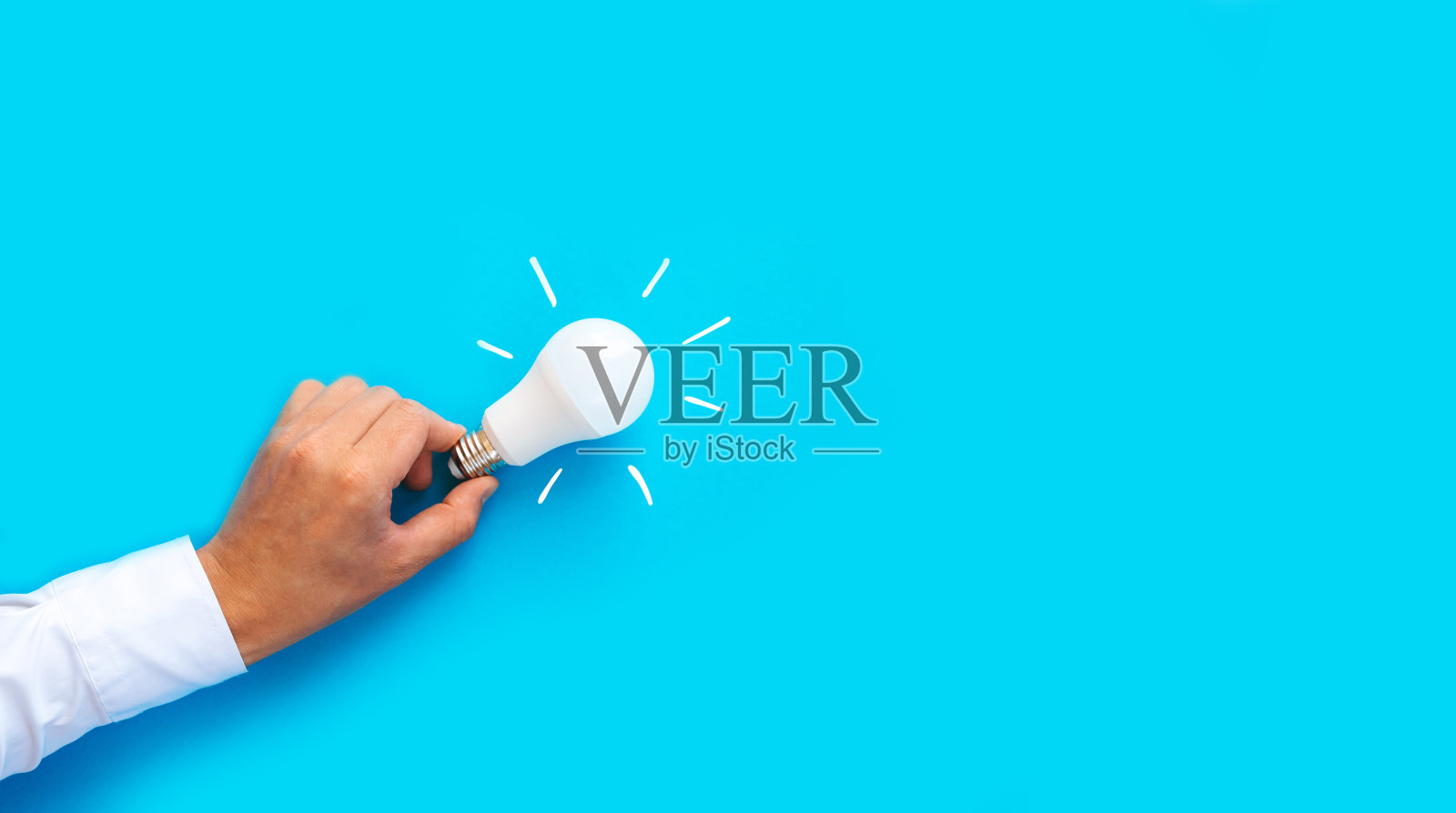 商人拿着蓝色背景的灯泡。动机成功的概念。灵感的想法。照片摄影图片