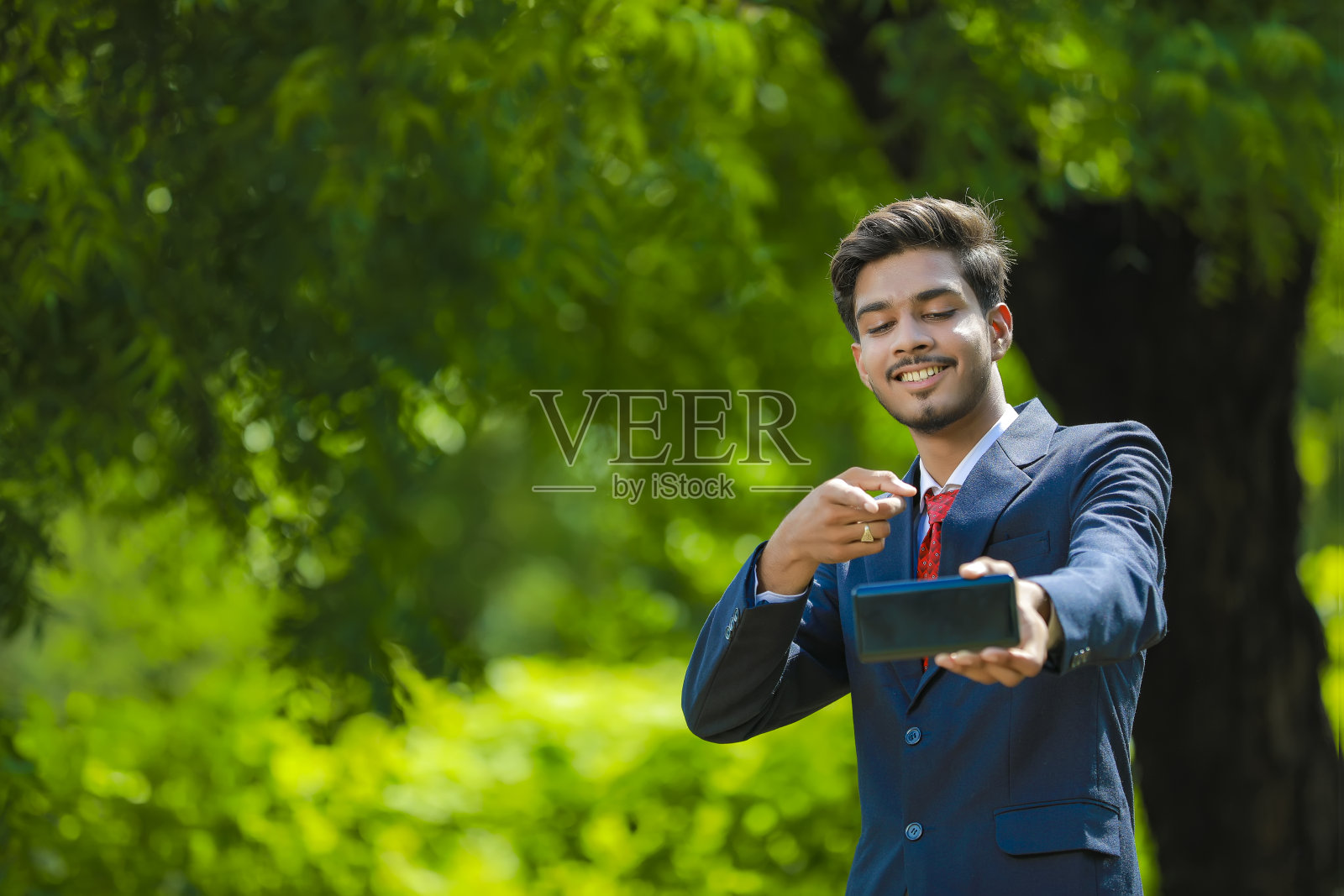 快乐的商人指着空白的智能手机屏幕照片摄影图片