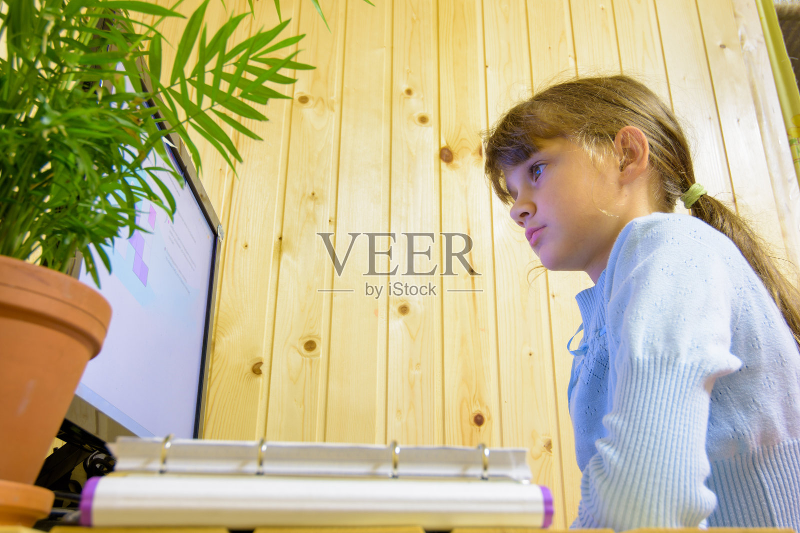 学生坐在显示器前面的桌子前，仔细地阅读任务照片摄影图片