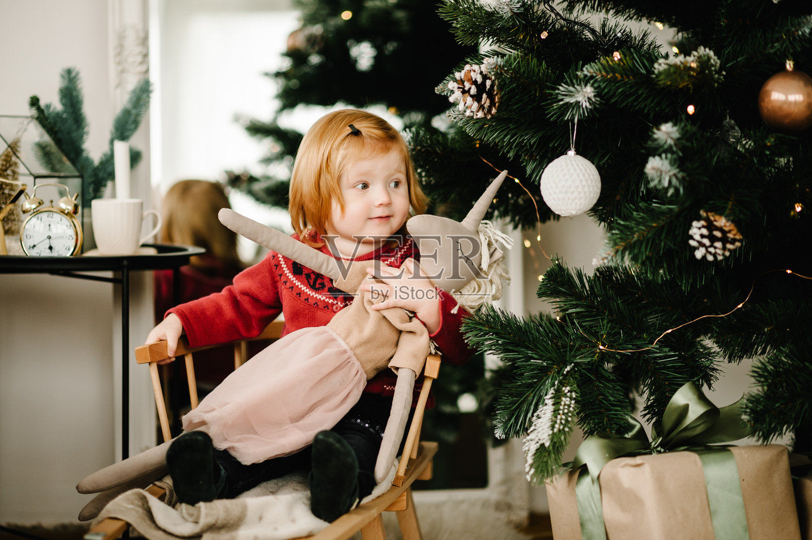 小女孩在家里的圣诞树附近玩玩具。新的2021年，假期和童年的概念。圣诞快乐，节日快乐。照片摄影图片