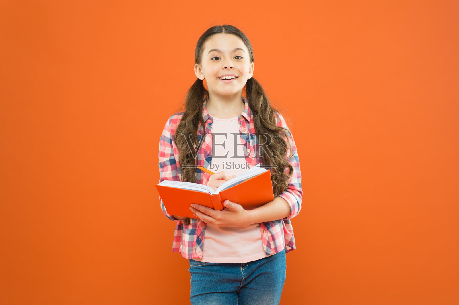 深入阅读。可爱的小孩读一本橙色背景的书。可爱的小女孩学习阅读和写作。家庭阅读和学校教育照片摄影图片