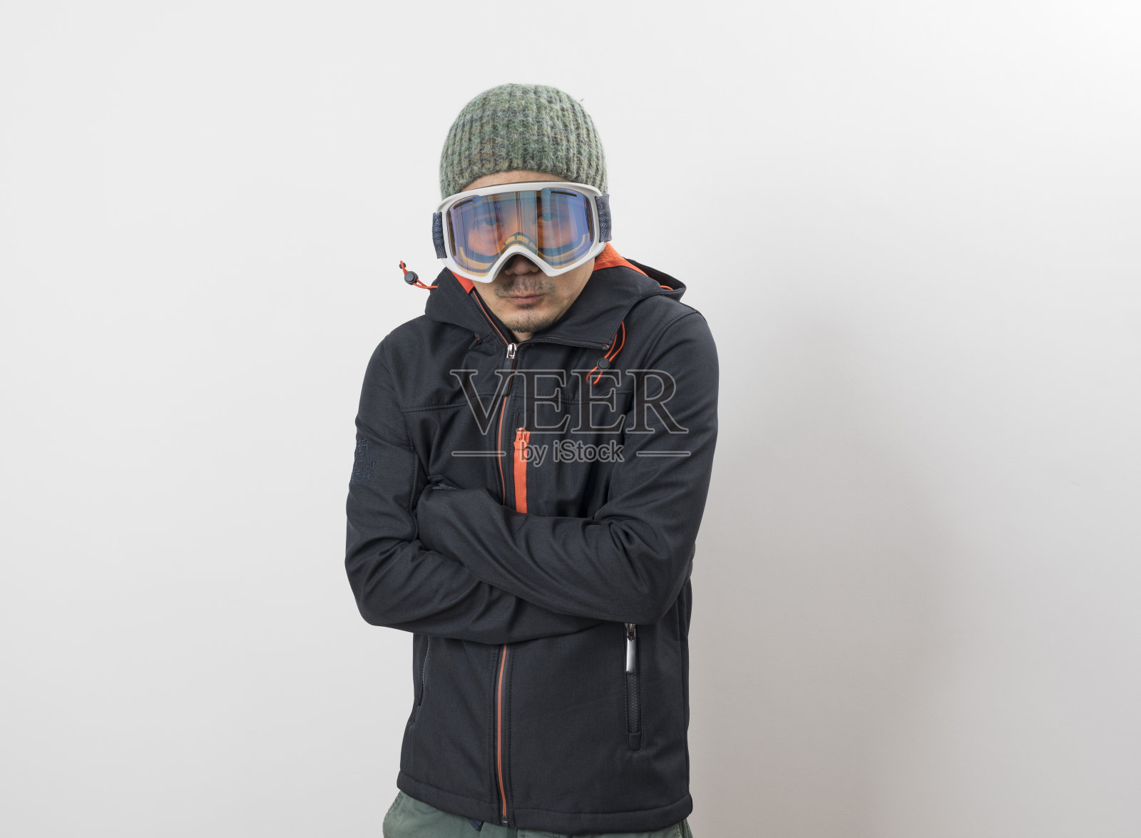 英俊的亚洲人穿着冬季大衣准备滑雪孤立在白色的背景。照片摄影图片