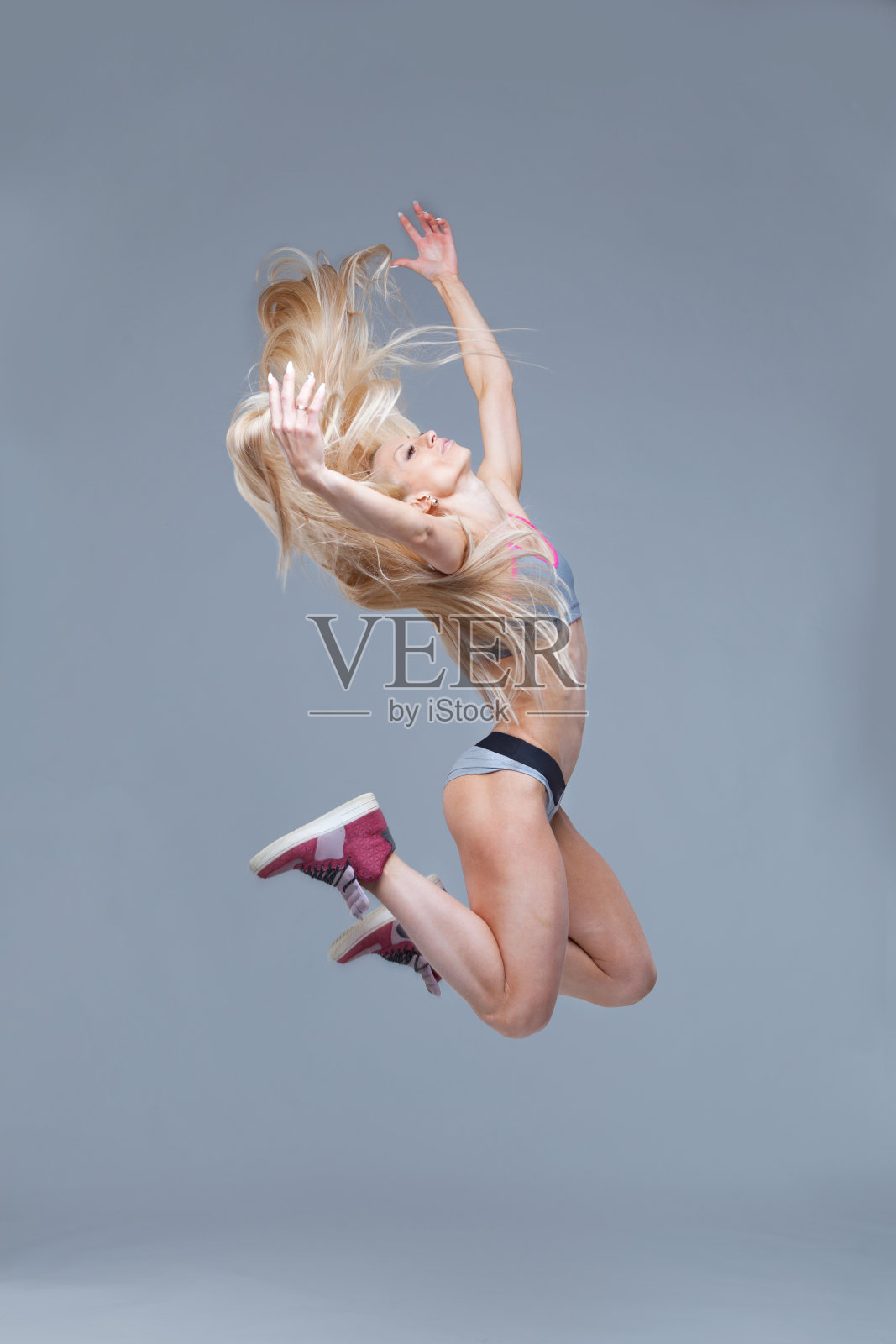 一个快乐的微笑健身女孩跳高的全长肖像孤立在灰色的背景照片摄影图片