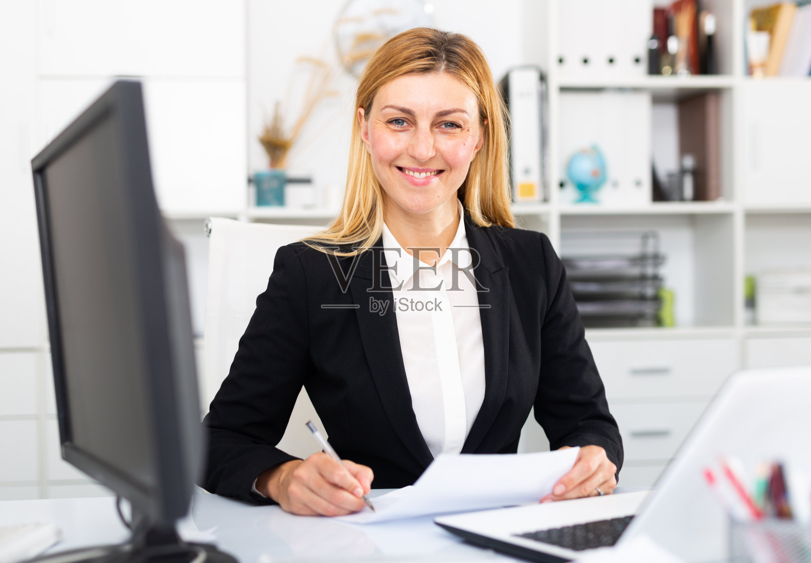 用笔记本电脑和文件工作的年轻女商人照片摄影图片