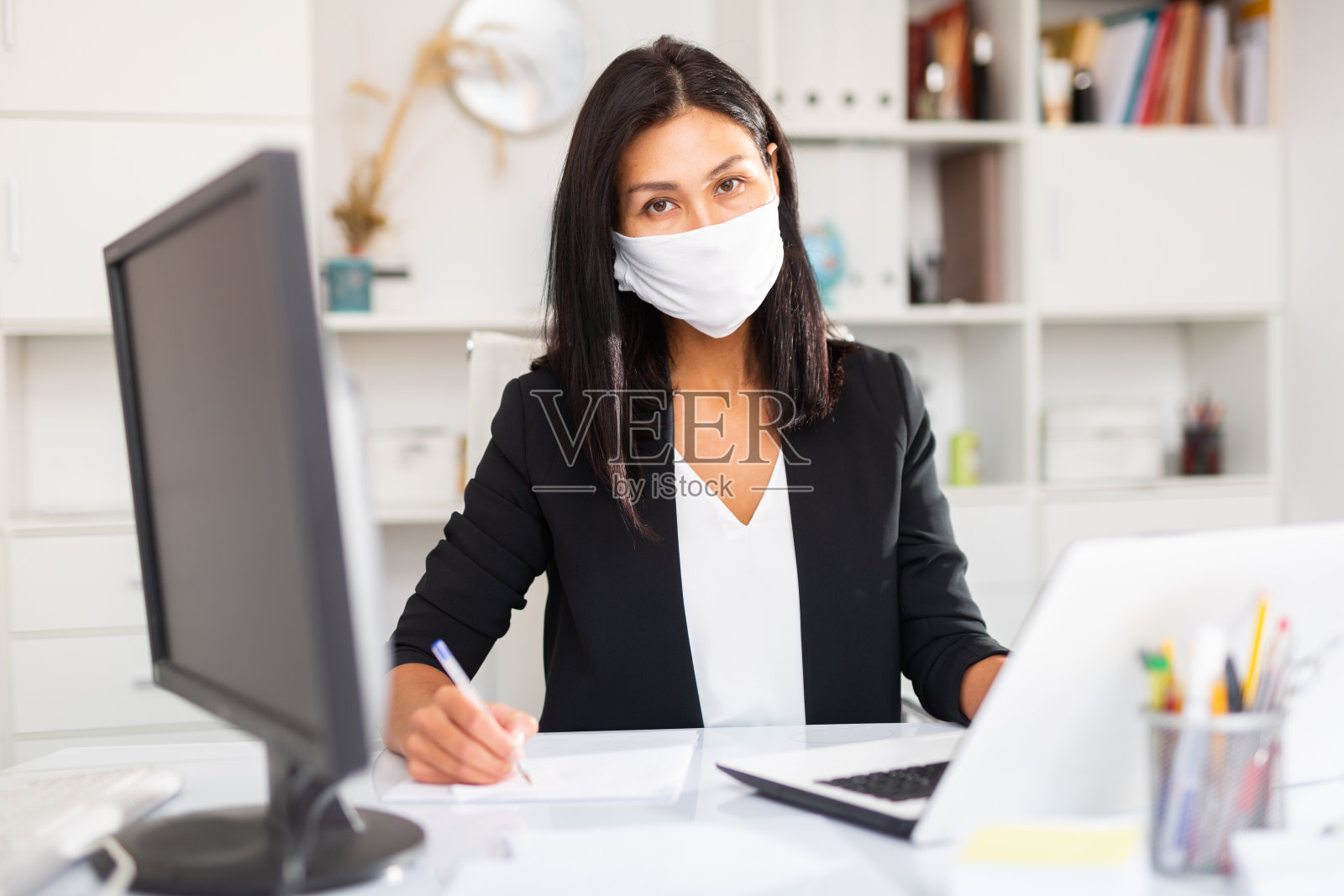 年轻的女商人戴着医用口罩用笔记本电脑工作照片摄影图片