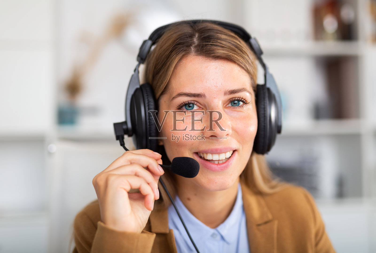 微笑的女接线员在办公室用耳机与客户交谈照片摄影图片