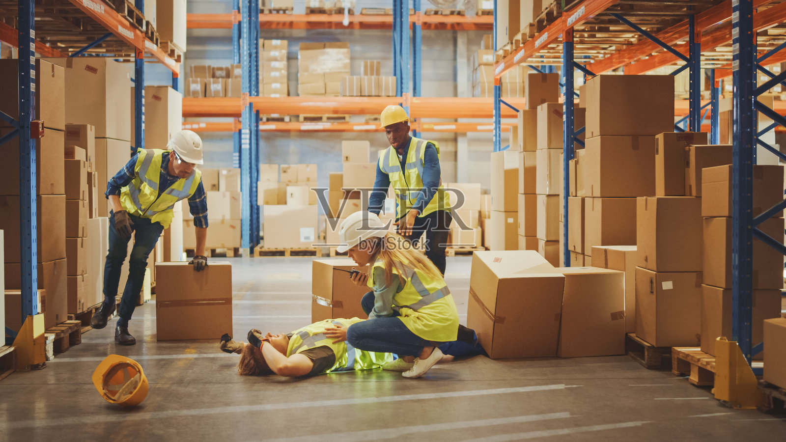 仓库工人在试图从货架上捡起硬纸盒时发生工伤事故。同事呼叫帮助和医疗援助。在工作中受伤。照片摄影图片