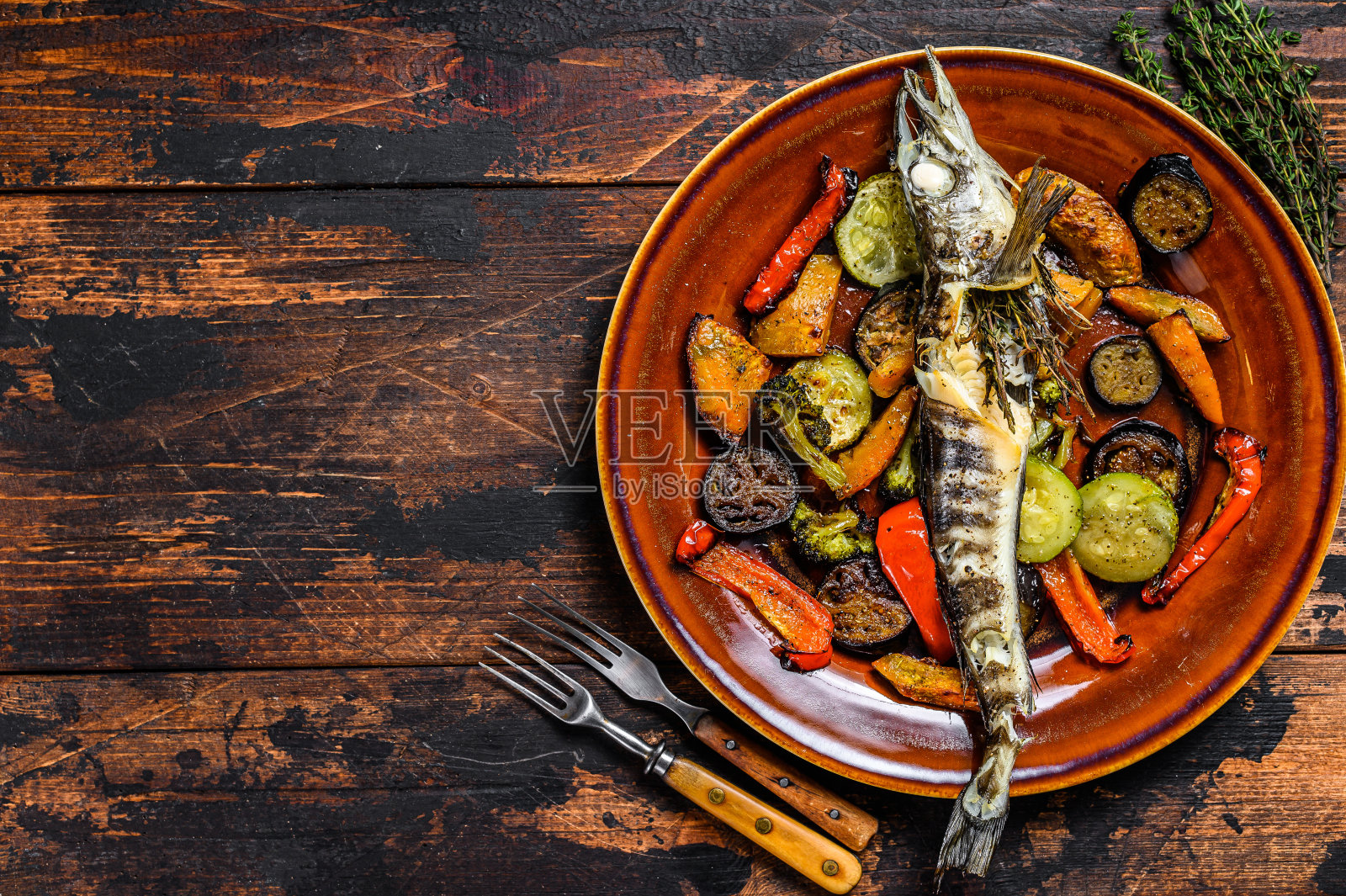 烤整条冰鱼配烤蔬菜。深色木制背景。俯视图照片摄影图片