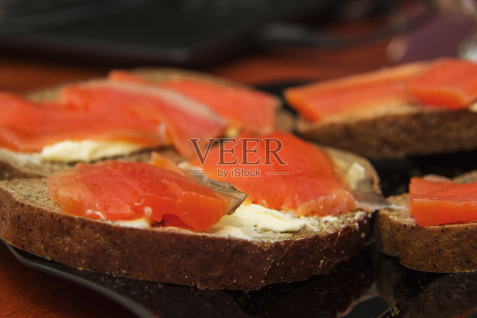 新鲜的鲑鱼三明治，咸鲑鱼，黄油和黑面包在黑色的盘子照片摄影图片