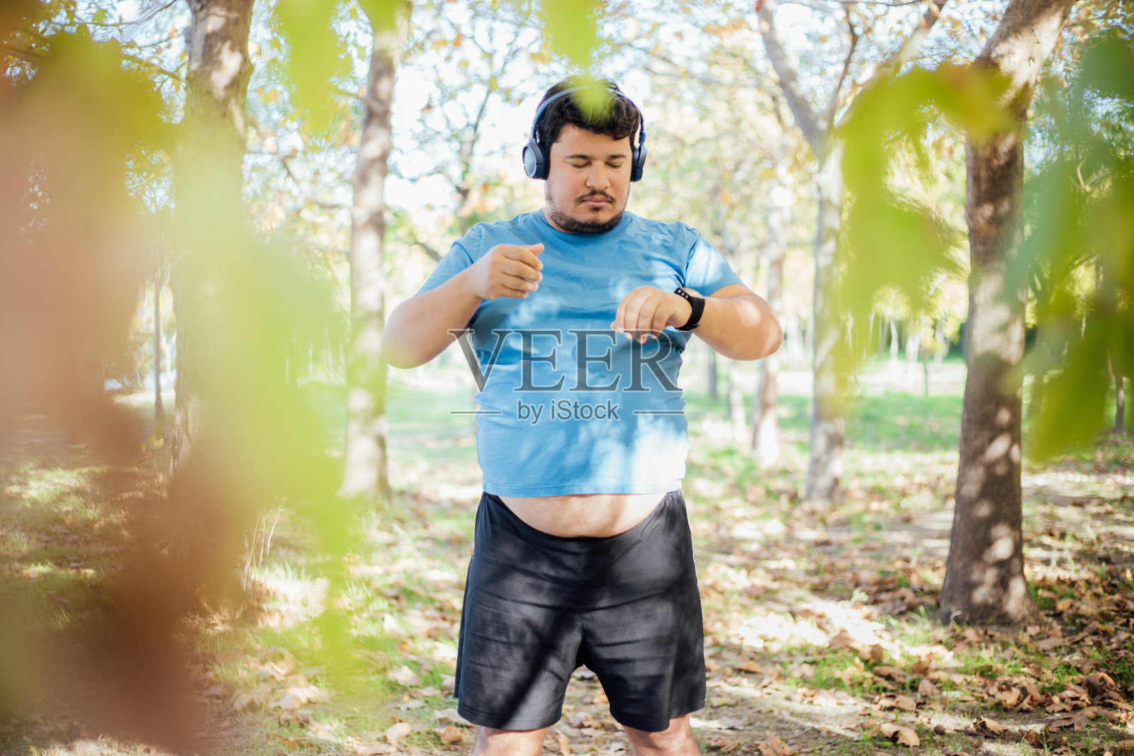 用无线耳机听音乐来激励自己锻炼的超重男士照片摄影图片