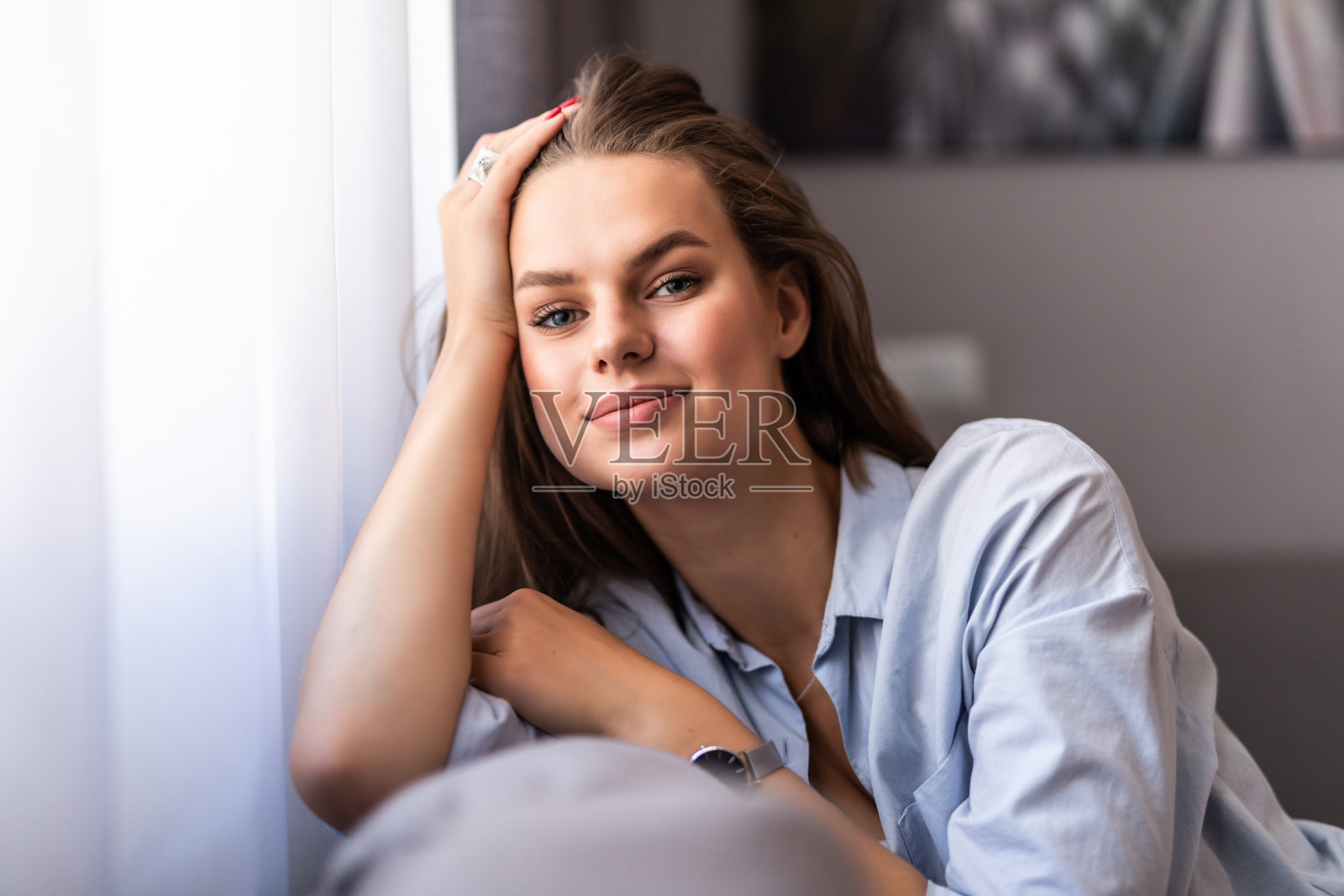 美丽的女人与白色完美的微笑看着相机坐在沙发上在家照片摄影图片