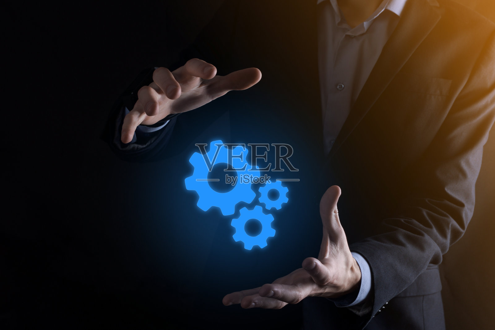 商务人士身着西装手持金属齿轮和齿轮机构，代表团队互动理念，手持齿轮组虚拟齿轮照片摄影图片