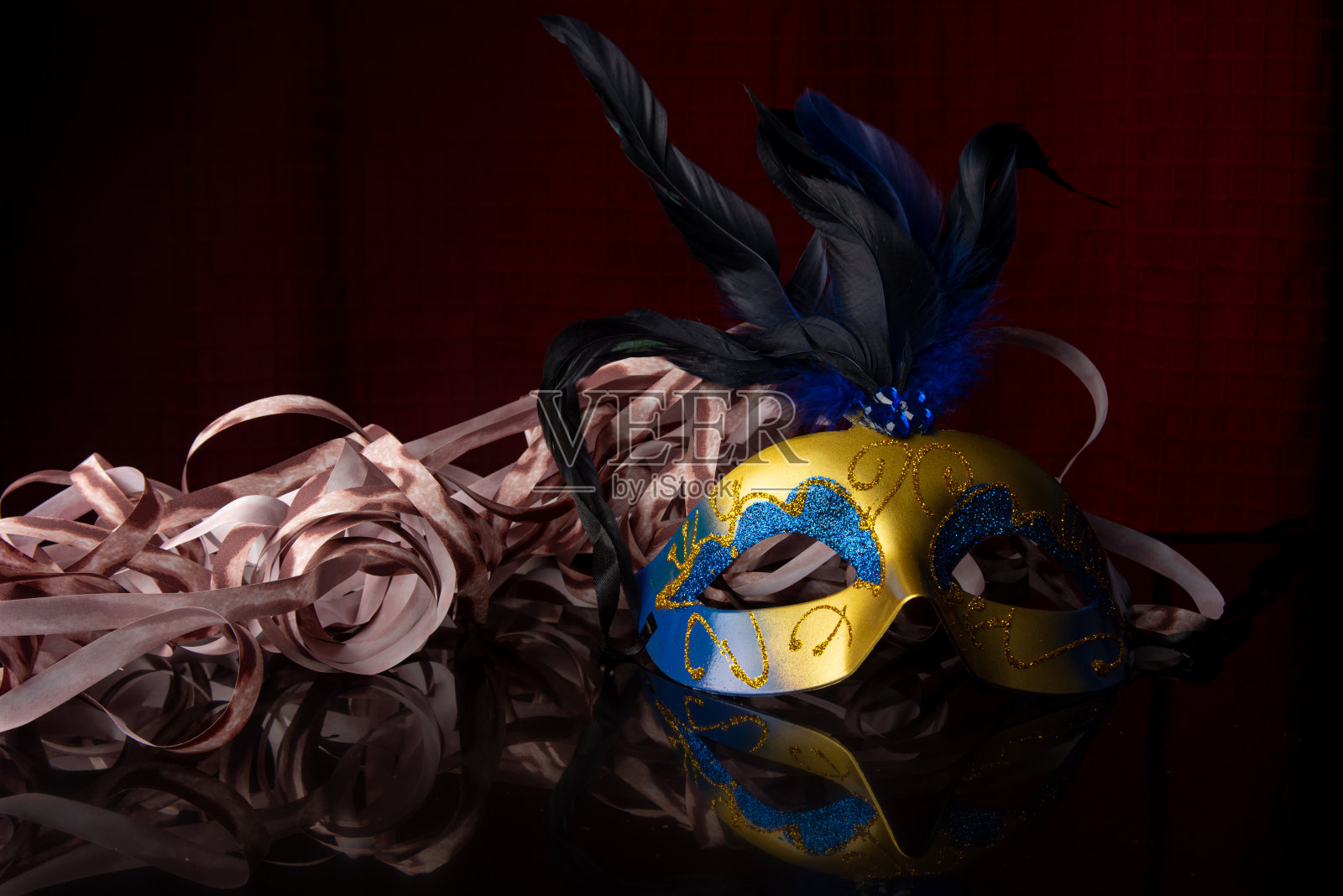 嘉年华面具，金色和蓝色威尼斯面具，黑色表面带彩带，选择性聚焦。照片摄影图片