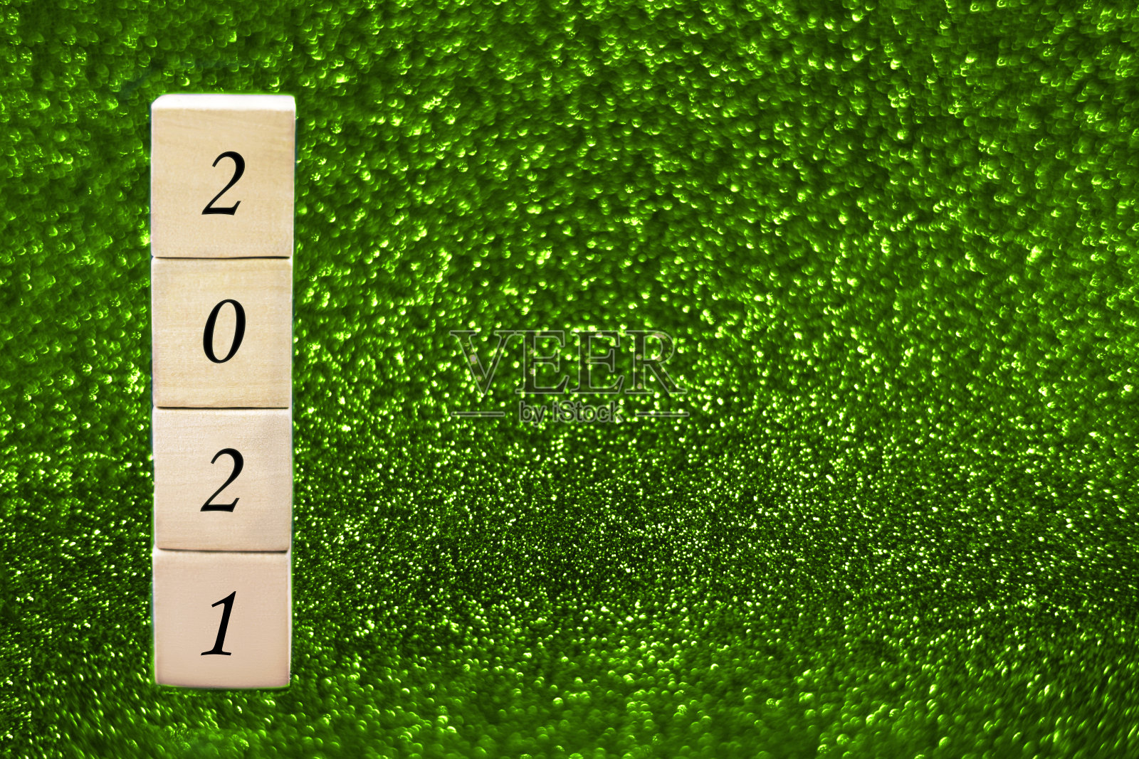 绿色闪闪发光的背景上有数字2021的木制立方体。照片摄影图片