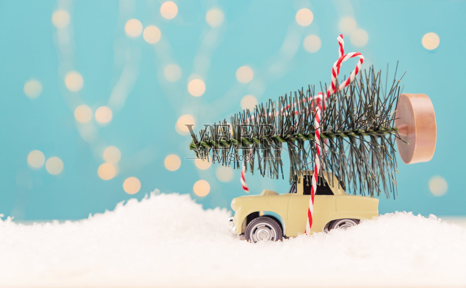 圣诞或新年贺卡与玩具汽车和圣诞树微型和圣诞散景灯的背景照片摄影图片