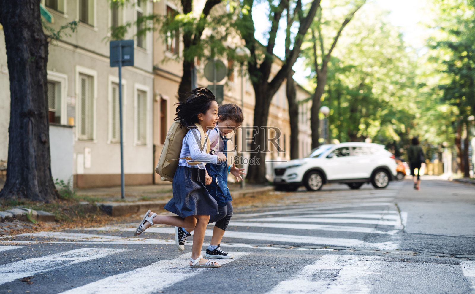 小女孩在户外穿过街道，冠状病毒概念。照片摄影图片