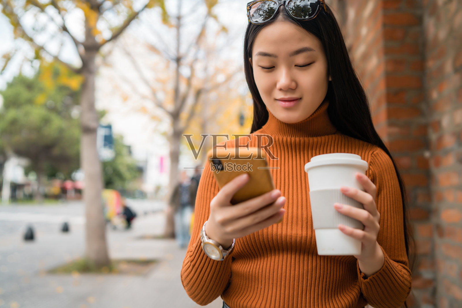 一个亚洲女人在街上用手机。照片摄影图片