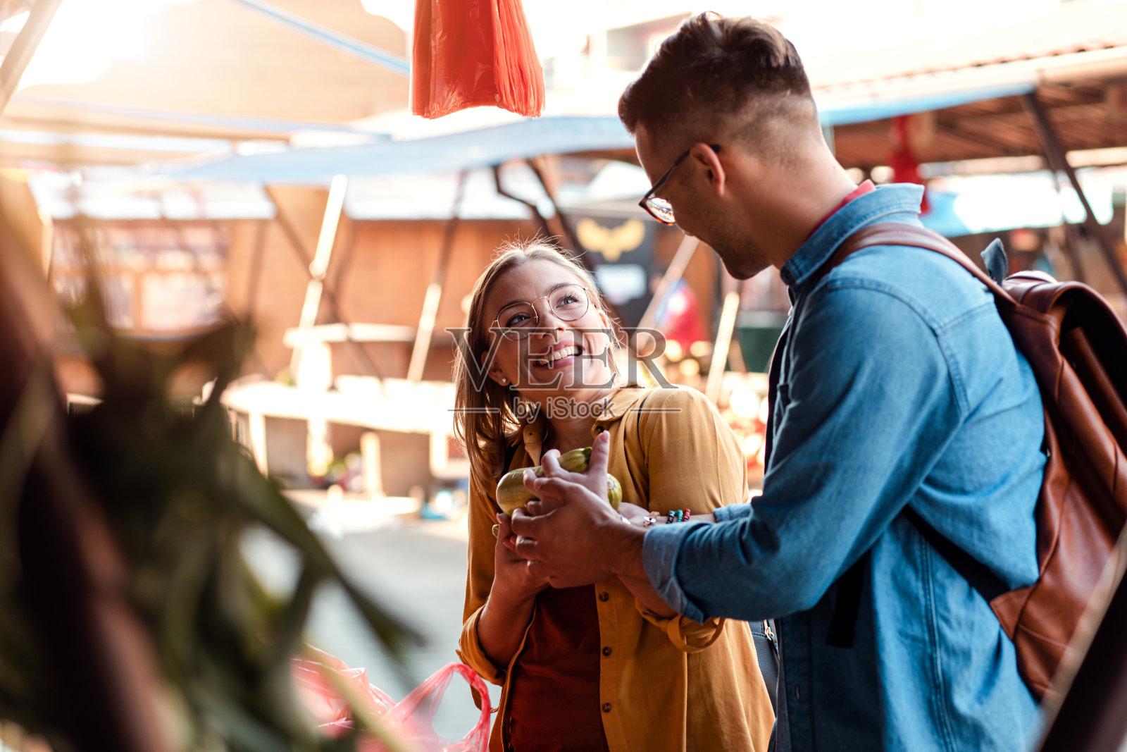 一对漂亮的年轻夫妇在户外市场买新鲜的蔬菜。照片摄影图片