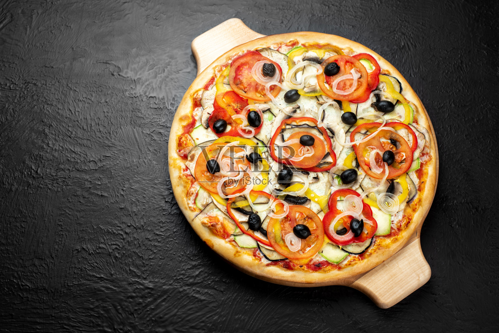 黑色背景的素食披萨，以番茄为原料，配以马苏里拉奶酪、橄榄、番茄、茄子、甜椒、西葫芦、洋葱和蘑菇照片摄影图片