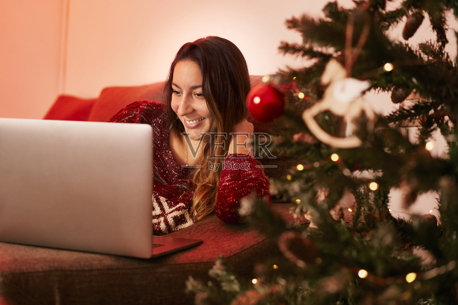 一个女人独自庆祝圣诞节，却在家上网。照片摄影图片