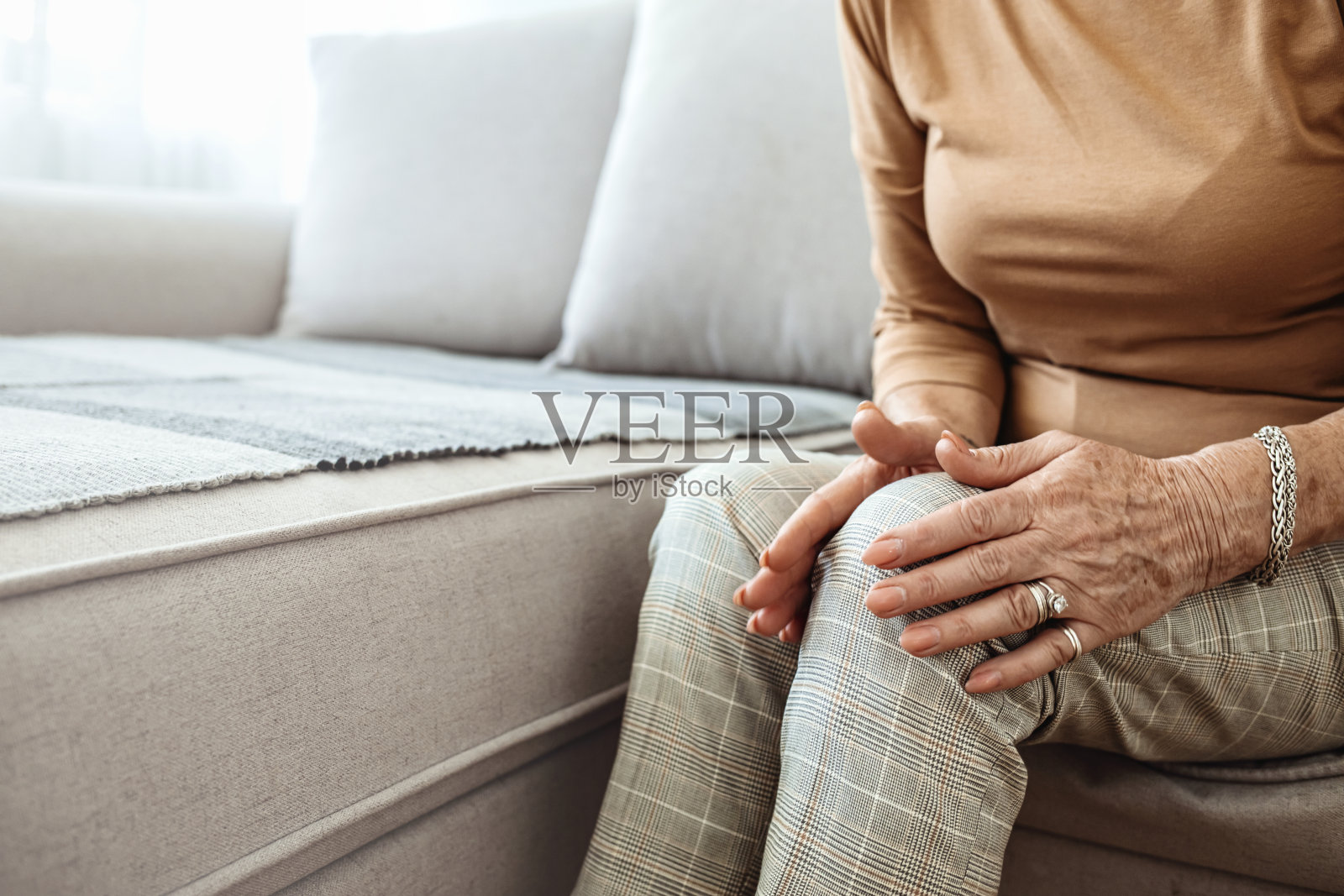 在家里忍受膝盖疼痛的老年妇女。照片摄影图片