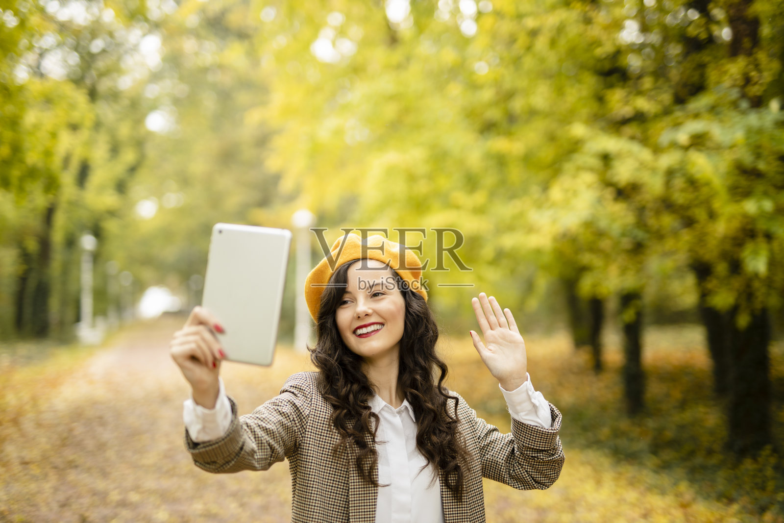 年轻时尚的女人有视频通话，享受在秋天的一天户外照片摄影图片