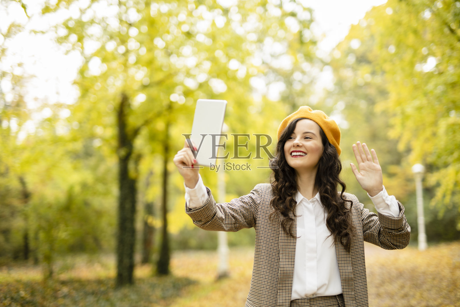 年轻时尚的女人有视频通话，享受在秋天的一天户外照片摄影图片