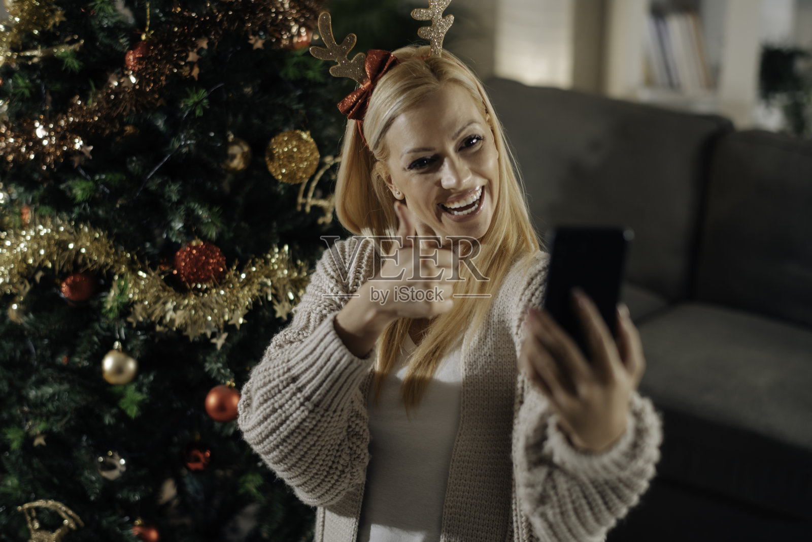 一个年轻快乐的女人旁边的圣诞树在一个视频电话库存照片照片摄影图片