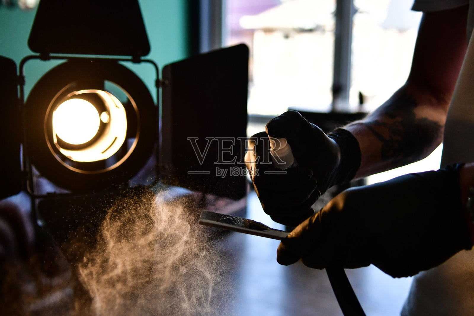 在探照灯光束前用发型师喷雾消毒剃刀照片摄影图片