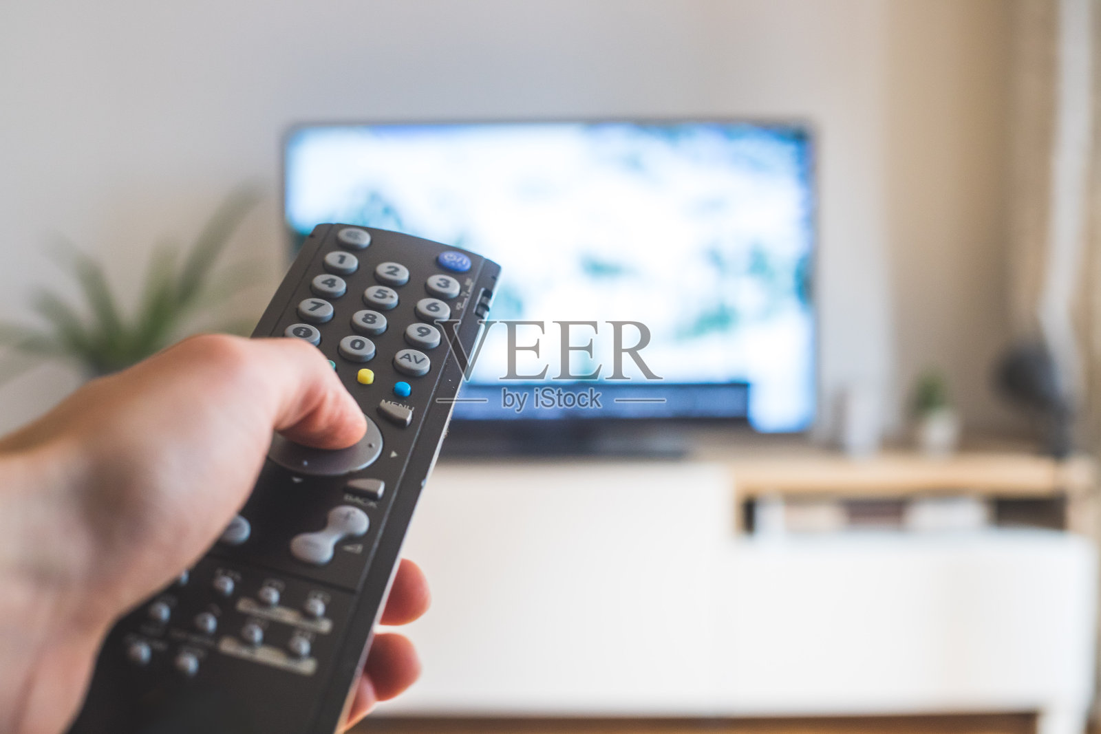 男性的手正握着电视遥控器，在智能电视上流媒体。照片摄影图片