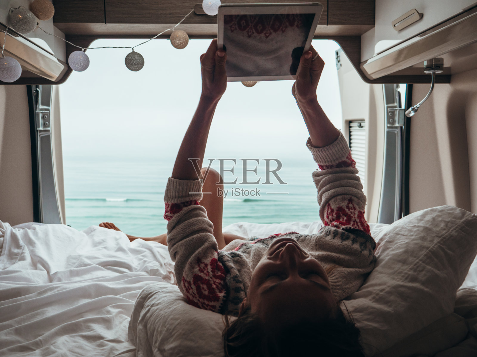 一个女人躺在货车后面用平板电脑看书照片摄影图片