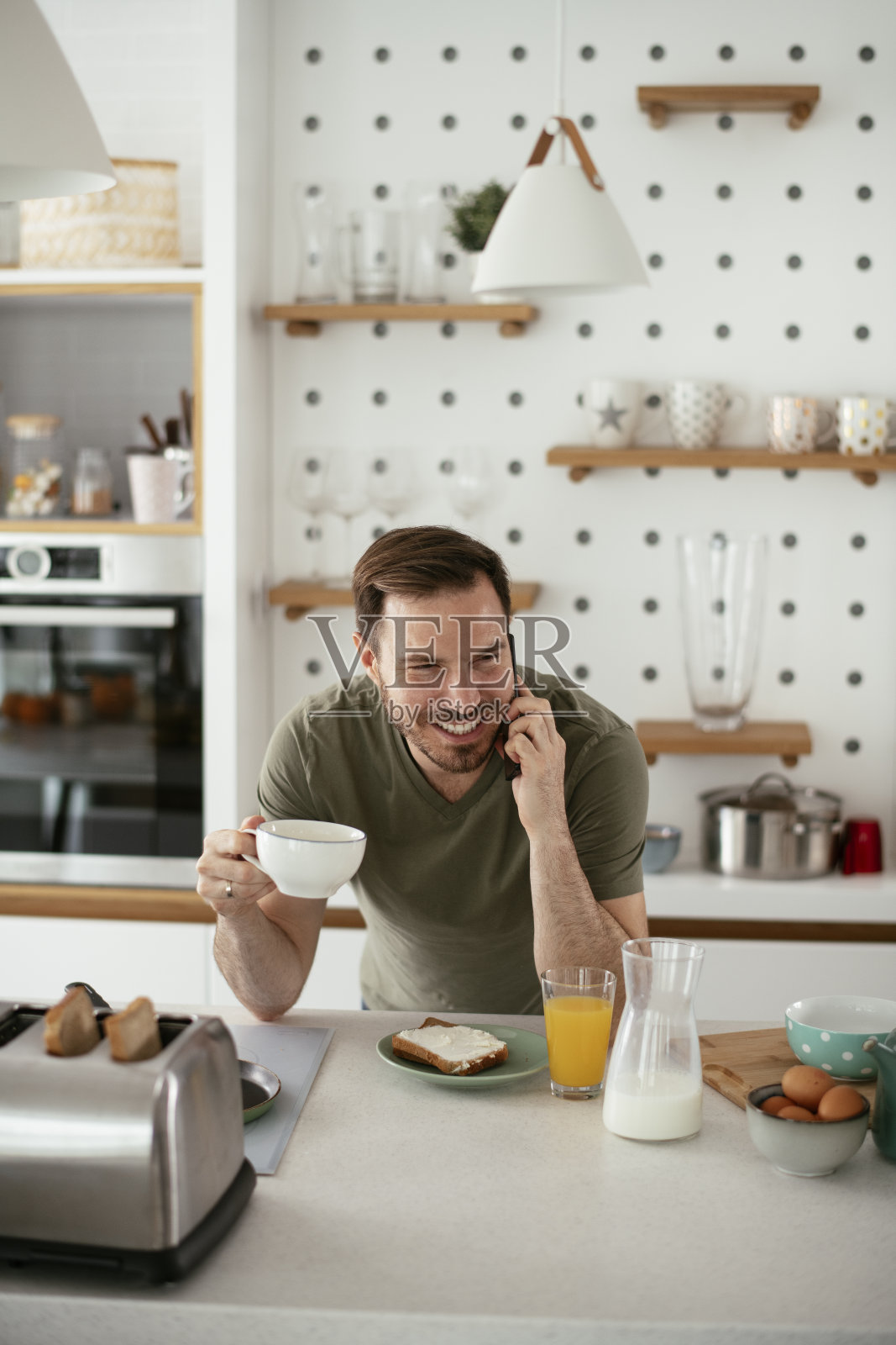 年轻人一边喝咖啡一边打电话。照片摄影图片