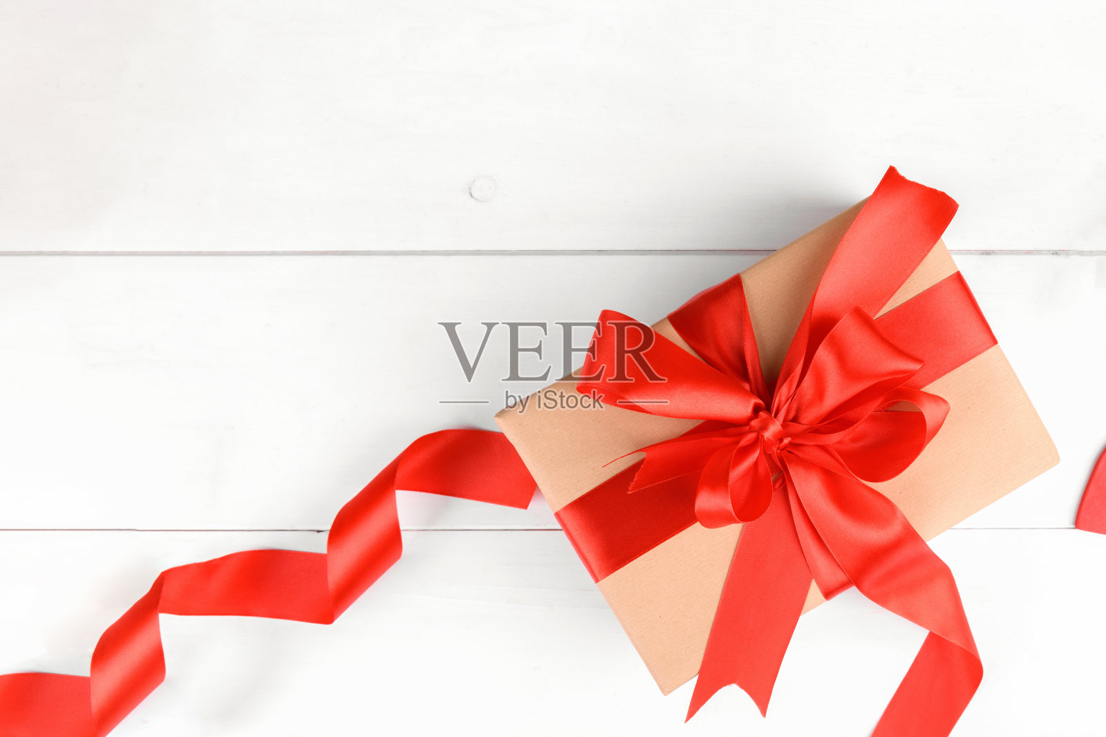 圣诞礼盒包装在工艺再生纸与红色丝带蝴蝶结在白色木制背景照片摄影图片