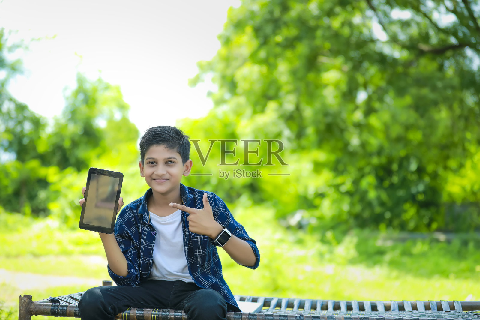 科技和人的概念-微笑的青少年男孩在蓝色衬衫展示智能手机与空白屏幕照片摄影图片