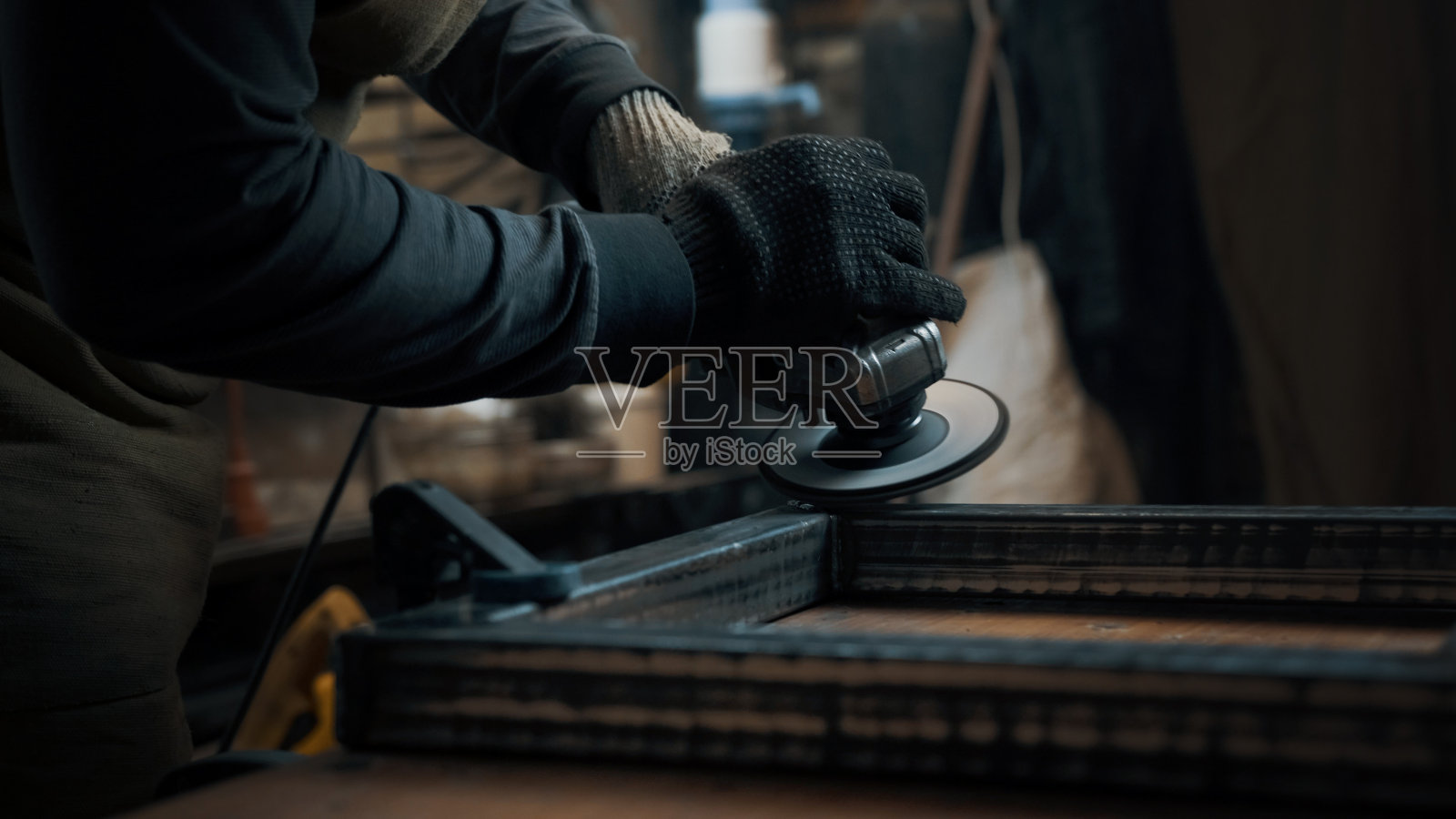 一个戴手套的人用圆锯切割金属，火花四溅。工作流程照片摄影图片